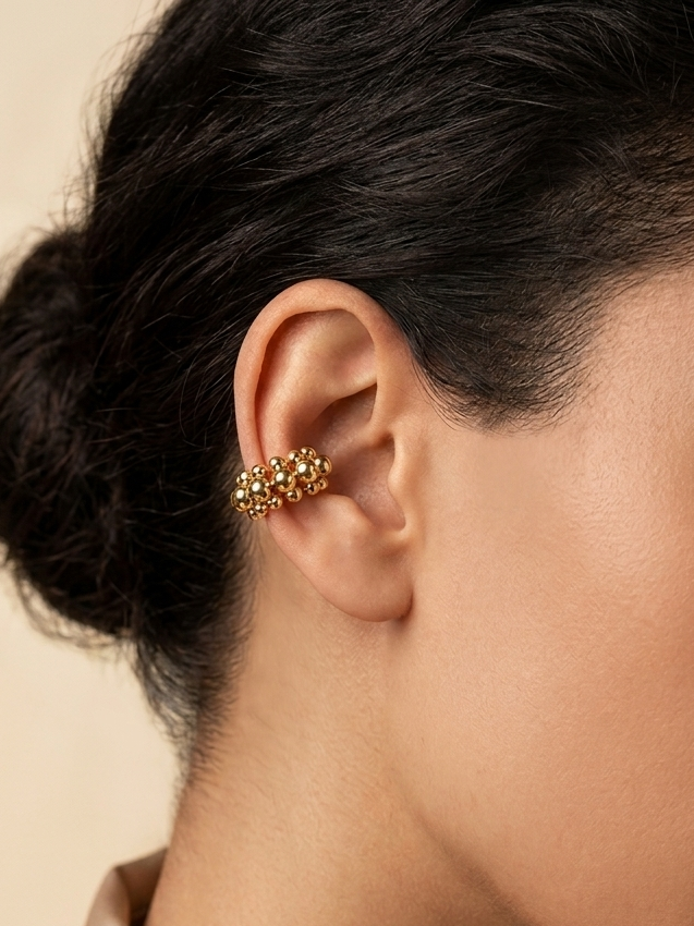 a model wearing a golden beaded earcuff