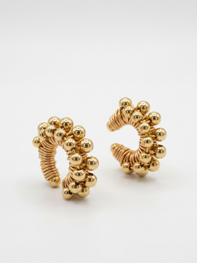 A pair of golden beaded earcuffs by showy llc
